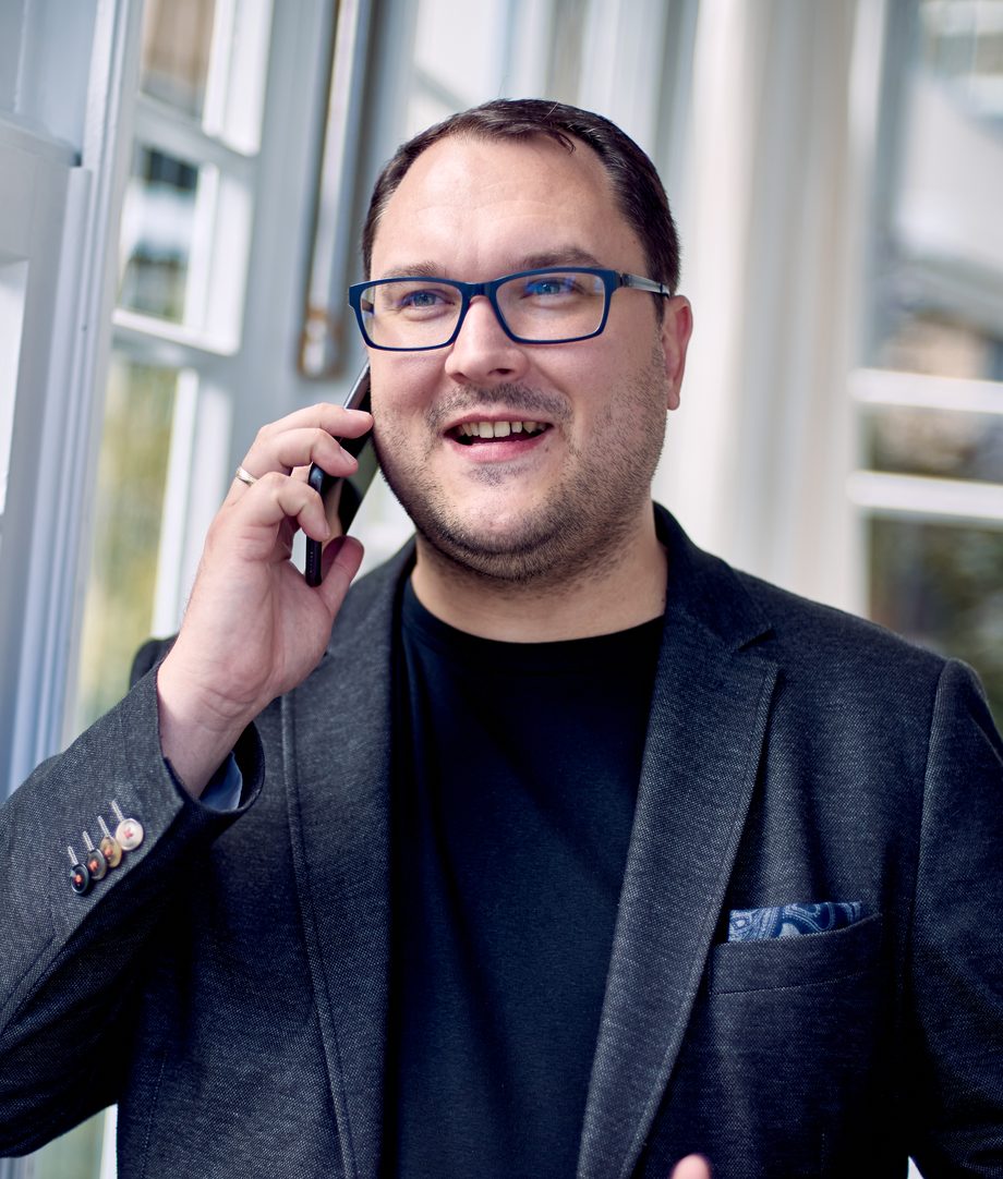 Thomas Schacht telefoniert lächelnd am Fenster